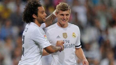 Write informative laconic excerpt under 30 words in mexican spanish for news below. Do not wrap it into quotation marks or html tags. Real Madrid fans and teammates paid tribute to a tearful Toni Kroos on Saturday as the midfielder played his last game at the Santiago Bernabeu before retiring from football this summer.Kroos -- who announced his decision to retire this week -- played 87 minutes of Madrid&apos;s 0-0 LaLiga draw with Real Betis.- Stream on ESPN+: LaLiga, Bundesliga, NWSL more (U.S.)It was his second-to-last game for the club, ahead of their Champions League final against Borussia Dortmund on June 1."It isn&apos;t easy," Kroos, 34, told Real Madrid TV. "I can only say thank you to Madrid fans, the club, my teammates, and this stadium. I&apos;ve always felt at home in these 10 years here. I couldn&apos;t ask for more. They&apos;ve been 10 unforgettable years."The Germany international, who will feature for his country at this summer&apos;s Euros before retiring, received a guard of honour from both teams ahead of the game, as fans behind one of the goals displayed a tifo saying "thank you, legend."Kroos took the captain&apos;s armband for the evening, and his Madrid teammates wore &apos;Kroos 8&apos; shirts before kick-off."Obviously it&apos;s a different feeling when you know it&apos;s your last game," he said. "I said I wanted to enjoy it and I did, I enjoyed these 85 minutes a lot, as I&apos;ve always enjoyed playing here. You play every two weeks here, but it&apos;s so special. I&apos;ll realise that in the years to come, when I don&apos;t have it."Kroos was substituted in the 87th minute to another long ovation, and was joined by his children on the pitch afterwards to receive more applause from the crowd."I was quite strong until the moment I saw my kids, they killed me!" he said, explaining his tears. "This is a special team, it&apos;s a good group. They&apos;ve all given me the respect I think I deserved. They aren&apos;t just good players, they&apos;re good people."Kroos -- who has won 22 trophies with Madrid, including four Champions Leagues and four LaLiga titles -- will have the chance to add another trophy to his collection at Wembley next weekend."I wanted to make [my retirement] official before this game, so that as of tomorrow we can forget about this subject," Kroos said. "The best way to leave would be winning a trophy."Real Madrid coach Carlo Ancelotti set it was a fitting tribute."It&apos;s a great farewell for a legend, a player who&apos;s done something extraordinary for this club," Ancelotti told Real Madrid TV. "I think it&apos;s the farewell he deserves."[He&apos;s] one of the greatest, who ended his career at the top. And let&apos;s hope we can win the 15th [European Cup] next Saturday."Ancelotti admitted that Madrid would have to adapt to life without Kroos next season."We&apos;ll see," he said in his post-match news conference, when asked what would change. "In terms of the atmosphere, the others have to take more responsibility. In a technical sense, we might have to play more direct football, with players with more energy." ,Toni Kroos se despide del Real Madrid con emotivo homenaje de compañeros y fans antes de retirarse este verano. Ganó 22 títulos con el club.