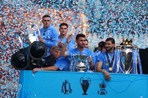 Write informative laconic excerpt under 30 words in mexican spanish for news below. Do not wrap it into quotation marks or html tags. Manchester City saw grey skies turn to blue on Sunday as they celebrated a record fourth successive Premier League title, with fans pouring into the streets of the city to cheer on their heroes once again.City proved their mettle by ending the title race in style with a 3-1 win over West Ham United on the final day of the season to finish on 91 points, two more than Arsenal, and become the first English club to win four league titles in a row.Players and staff waved to fans as confetti rained down and blue smoke flares were lit along the route of the open-top bus, just hours after thousands of people took part in the Great Manchester Run.Neither the weather nor the anti-climax of the ceremony taking place the day after the FA Cup final defeat by arch-rivals Manchester United 2-1 could dampen the spirits as flags, bananas and even a blow-up Jack Grealish dummy were held aloft in triumph."We&apos;re delighted with this season but we want to go back and try and win more," said player of the year Phil Foden, who scored 19 league goals."It&apos;s the hunger inside me to win trophies. We have a great group. It&apos;s been a special season. Obviously it&apos;s something nobody&apos;s done before, an incredible feeling, we couldn&apos;t have done it without the staff or the fans," he added.City&apos;s ambition to keep winning trophies, and the disappointment of losing the FA Cup, was also echoed by Portugal international Bernardo Silva."Obviously last night was frustrating but we have to forget that and celebrate four in a row. It&apos;s been a very good season for us," he said.Having won the treble last year, Pep Guardiola&apos;s side added the Super Cup and Club World Cup to their haul this season along with the league title.The Spanish manager, named Premier League manager of the year, smiled for the fans and was thrilled with the celebrations despite taking the blame for his side missing out on a second successive domestic double. ,Manchester City celebra su cuarto título consecutivo de la Premier League con una victoria 3-1 sobre West Ham United, totalizando 91 puntos y haciendo historia en el fútbol inglés.