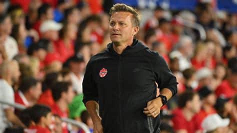 Write informative laconic excerpt under 30 words in mexican spanish for news below. Do not wrap it into quotation marks or html tags. ORLANDO, Fla. -- Canada coach Jesse Marsch said he and his team are "not satisfied" yet after qualifying for the Copa América quarterfinals for the first time, on their tournament debut.Canada drew 0-0 with Chile at Inter&Co Stadium in Orlando, Florida, on Saturday to finish second in Group A on four points, behind world champions Argentina.They&apos;ll face the winners of Group B -- with Venezuela currently leading the group -- in the last eight on July 5 at AT&T Stadium in Arlington, Texas."We are not satisfied. The group is not satisfied. They want to keep going," Marsch said in his post-match news conference. "They know, no matter who our next opponent is, it will be a difficult match. But they believe in themselves. We&apos;re excited for this next challenge."Chile defender Gabriel Suazo was sent off after receiving his second yellow card in the 27th minute to give Canada a man advantage, but the game remained tight, with Canada substitute Tani Oluwaseyi having a goal disallowed for offside in added time."I&apos;m challenging them to grow and get better, to be more savvy professionals, more mature players," Marsch said. "I&apos;ve been incredibly impressed by them, from the first training session. I&apos;m enjoying being their coach. I&apos;m proud of this accomplishment. But again, we&apos;re not satisfied."Jesse Marsch has guised Canada to the Copa América quarterfinals at the first attempt. Julio Aguilar/Getty ImagesCanada were beaten 2-0 by Argentina in the tournament&apos;s opening game in Atlanta on June 20, before beating Peru 1-0 five days later.Saturday&apos;s 0-0 draw with Chile was enough to progress to the quarterfinals, after Argentina beat Peru 2-0 in the night&apos;s other game."I thought we would get out of the group, I really did," Marsch said. "I knew it would be a big challenge. Mostly, I was trying to prepare the team for the savviness and intelligence of what South American teams are."We&apos;ve had to grow up, and understand what South American edge and power and competitive will is like ... We&apos;ve grown. Not just from a football perspective, but a maturity perspective."Marsch only took charge of Canada in May, having been out of management since leaving Leeds in February 2023."When I took the job, I knew the group," Marsch said on Saturday. "I knew the task at hand was going to be difficult. But we&apos;ve played five matches, and had clean sheets in eight of the 10 halves."There was a lot of talk about defensive frailties, and no-one was sure how the team would be able to defend. But the entire team has been tactically very organised, disciplined. We&apos;ve looked athletic and strong in every match.""We need a little bit more of an edge," Marsch added. "I need them to be mad at me sometimes when they don&apos;t play, I need them to be a bit angry with the coach on certain decisions, but we&apos;ll get there. This is part of the maturation, the demand and expectation we have for each other, what this is really going to require."Chile -- who won the Copa América in 2015 and 2016 -- failed to score in their three games at the tournament."This team can score goals," assistant coach Sergio Santin insisted in his post-match news conference, with coach Ricardo Gareca serving a one-match ban after his team returned to the field late for the second half of their game with Argentina."We believe that these forwards will score goals. In the Copa América, the [lack of] goals, I have to accept that. But I believe, and we believe, in the forwards we have." ,El técnico de Canadá, Jesse Marsch, dice que el equipo no está satisfecho tras clasificar a cuartos de final de la Copa América en su debut.