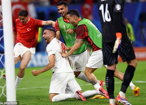 Write informative laconic excerpt under 30 words in mexican spanish for news below. Do not wrap it into quotation marks or html tags. Turkey overcame stiff resistance from 10-man Czechia in a 2-1 win on Wednesday with goals from Hakan Çalhanoglu and Cenk Tosun to set up a Euro 2024 last-16 clash with Austria and send their opponents home.Czechia, quarterfinalists at the last tournament, needed victory to stand any chance of advancing, but the 20th-minute dismissal of midfielder Antonín Barák for a harsh second yellow card hit them hard.In a chaotic end to the game, Czechia&apos;s Tomás Chorý was also given a red card in a melee at the final whistle.The referee showed 18 cards in total, two red and 16 yellow, to set a new Euros record.Both teams pressed hard from the start in a raucous atmosphere on a hot night, Turkish fans marching to the game and outnumbering the Czechs thanks to their huge diaspora in Germany.Thirty-year-old playmaker Calhanoglu&apos;s 50th-minute goal was a first at his third Euros, triggering flares and delirium from fans. He scored with a low shot across goalkeeper Jindrich Stanek, who appeared to hurt his shoulder with a save just before and went off injured after the goal.Turkey players celebrate after beating Czechia at the European Championship.Teenager Arda Güler inexplicably missed a close-range sitter to put Turkey two ahead and Czechia immediately equalised, Tomás Soucek prodding home in the 66th minute after a long throw caused chaos to set up a thrilling finale.Tosun struck Turkey&apos;s winner in stoppage time, sparking wild scenes on his bench and among Turkish fans. The result banished the Turks&apos; dark memories of Euro 2020 where they went home after conceding eight goals in three defeats."We all fought very well together," said defender Mert Muldur. "We had a hard time against such teams in the past ... I think we have improved ourselves."After two wins in three games, Turkey finished second behind Portugal in Group F on goal difference and will play Austria in the last 16 on July 2 in Leipzig."When we talked with our friends before the camp, our only goal was to get out of the group. We kept our promise and left the group. Now we will proceed step by step," said Turkey winger Baris Alper Yilmaz. "We are very happy."The Czechs finished bottom of the group with one point."It is a disappointment because we all wanted to advance," captain Soucek said, lamenting how the "disrespectful" soft red card had affected the game."We were happy to get the equaliser," he added. "Everyone did the maximum. The morale was huge. Just a sad end ... But that is football."Portugal were already guaranteed top place in the group but lost to Georgia, who went through as one of the best third- placed finishers.,Turquía vence a la República Checa 2-1 en la Euro 2024 para avanzar a octavos, con expulsiones y récord de tarjetas.