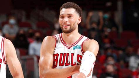 Write informative laconic excerpt under 30 words in mexican spanish for news below. Do not wrap it into quotation marks or html tags. - Zach LaVine, jugador de los Chicago Bulls, tuvo una temporada 2021-2022 en la cual vio disminuir su promedio de puntos a 24.4 por juego debido a una lesión en la rodilla y la llegada de nuevos jugadores al equipo. - A pesar de la lesión y la competencia en el equipo, LaVine sigue siendo un jugador valioso para los Bulls, contribuyendo con promedios de 4.6 rebotes, 4.5 asistencias y 2.8 triples por juego. - LaVine ha firmado una extensión de contrato máximo con los Bulls y se espera que esté listo para el inicio de la temporada 2022-2023 tras someterse a una cirugía para corregir su lesión en la rodilla.,Zach LaVine de los Chicago Bulls baja promedio de puntos a 24.4 por lesión, seguirá siendo clave con 4.6 rebotes y 4.5 asistencias. Extensión de contrato y cirugía para 2022-23.