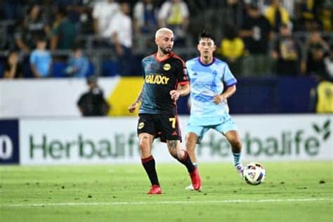 Write informative laconic excerpt under 30 words in mexican spanish for news below. Do not wrap it into quotation marks or html tags. playRicard Puig scores a well-placed goal to extend LA Galaxy&apos;s lead (0:57)Ricard Puig scores a well-placed goal to extend LA Galaxy&apos;s lead. (0:57)Jul 18, 2024, 02:26 AM ETJoseph Paintsil recorded one goal and two assists to help the LA Galaxy produce a 3-2 victory over the Colorado Rapids on Wednesday night at Carson, Calif.Diego Fagundez and Riqui Puig added goals and Gabriel Pec had two assists as the Galaxy (13-5-7, 46 points) bounced back from a 2-0 road loss against FC Dallas on Saturday.The win, combined with Real Salt Lake and Los Angeles FC playing to a 1-1 tie on Wednesday, moved the Galaxy into first place in the Western Conference. The Galaxy haven&apos;t lost at Carson this season; their lone "home" loss came against LAFC on July 4 at the Rose Bowl in Pasadena, Calif.Kevin Cabral and Cole Bassett scored goals for the Rapids (11-9-5, 38 points), who fell to 5-2-1 over their past eight matches.The setback was just Colorado&apos;s second to the Galaxy since the start of the 2018 season. The Rapids hold a 7-2-3 edge during that span.The Galaxy prevailed despite being without leading scorer Dejan Joveljic (hamstring) for the second straight match.LA goalkeeper John McCarthy made seven saves. Colorado&apos;s Zack Steffen had six stops.Neither team scored in the second half after the Galaxy led 3-2 after a wide-open first half.LA Galaxy players celebrate Riqui Puig&apos;s goal. William Navarro-USA TODAY SportsLA opened the scoring in the 12th minute when Pec delivered a pass toward Fagundez, who collected the ball with his chest, had it drop to his feet and then smacked a right-footed shot past Steffen. It was Fagundez&apos;s fourth goal of the season.Colorado knotted the score in the 32nd minute. Jonathan Lewis had the ball to the left of the net and sent a soft pass to a charging Cabral, who reached back with his left leg and knocked the ball past McCarthy. It was Cabral&apos;s fifth goal of the season.The Galaxy moved back ahead in the 38th minute after Pec started a long run on his own side of the field. As he closed in on shooting position, he sent the ball over to Paintsil, who booted a right-footer into the net for his seventh goal of the year.Five minutes later, LA made it 3-1, and this time, it was Paintsil delivering a stellar pass. Puig got the ball and sent a right-footer into the side netting just inside the left post for his seventh goal of the season, as well.The Rapids cut their deficit to one in the 10th minute of first-half stoppage time. Rafael Navarro lined up for a penalty kick and McCarthy made the save on his shot, but Bassett headed in the rebound for his eighth goal of the campaign.LA outshot Colorado 16-13, with both squads putting nine attempts on target. ,Joseph Paintsil anotó un gol y dos asistencias para la victoria 3-2 del LA Galaxy sobre Colorado Rapids con un gol de Ricard Puig.