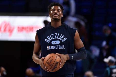 Write informative laconic excerpt under 30 words in mexican spanish for news below. Do not wrap it into quotation marks or html tags. Jaren Jackson Jr. tuvo una destacada temporada pasada, ganando el premio Jugador Defensivo del Año, siendo seleccionado por primera vez en el All-Star y liderando la liga en tapones. Mejoró sus promedios de puntos, rebotes y tiros libres, al tiempo que mantuvo un alto porcentaje de tiros de campo. Debido a una lesión en el pie, Jackson se perdió casi el primer mes de la temporada 2022-2023. Sin embargo, regresó con fuerza y continuó demostrando ser uno de los protectores de aro más destacados de la liga y una amenaza ofensiva multifacética. Para la próxima temporada, los Grizzlies se enfrentarán a un período de adaptación sin Ja Morant (suspensión) y sin Tyus Jones. Se espera que Marcus Smart comience como base titular, lo que podría resultar en más oportunidades de tiro para Jackson.,Jaren Jackson Jr. destaca en defensa y ofensiva con altibajos por lesión. Los Grizzlies enfrentan cambios en el equipo para la próxima temporada.