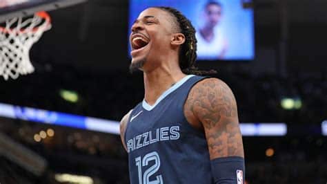 Write informative laconic excerpt under 30 words in mexican spanish for news below. Do not wrap it into quotation marks or html tags. El base de los Grizzlies de Memphis, Ja Morant, ha sido suspendido por 25 partidos al comienzo de la temporada 2023-24 debido a su comportamiento inapropiado en las redes sociales, donde fue visto exhibiendo un arma de fuego en Instagram en dos ocasiones diferentes durante la temporada baja. El equipo de los Grizzlies ha realizado un cambio significativo en la posición de base al despedir a Tyus Jones y adquirir a Marcus Smart en un acuerdo de tres equipos poco después de conocerse la suspensión de Morant. Morant tuvo una temporada destacada en 2022-23, promediando 27.4 puntos y mostrando su habilidad para finalizar en la canasta, pero su bajo porcentaje de tiros libres y su historial de lesiones plantean riesgos para su rendimiento fantasy.,Ja Morant de los Grizzlies suspendido 25 partidos por comportamiento inapropiado en redes sociales. Equipo firma a Marcus Smart tras cambio significativo. Riesgos con Morant fantasy.