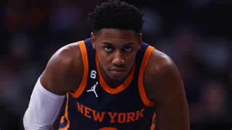 Write informative laconic excerpt under 30 words in mexican spanish for news below. Do not wrap it into quotation marks or html tags. RJ Barrett, jugador de los New York Knicks, mostró promesa en su temporada pasada, promediando 19.6 puntos, 5.0 rebotes y 2.8 asistencias en 34 minutos por partido. A pesar de sus números sólidos, Barrett tuvo problemas de eficiencia, ya que disparó un 43% desde el campo, un 31% desde la línea de tres puntos y un 74% desde la línea de tiros libres. La llegada de nuevos jugadores al equipo de los Knicks, como Julius Randle y Jalen Brunson, así como las adquisiciones de Josh Hart y Donte DiVincenzo, podrían afectar el rol y el volumen de juego de Barrett en la próxima temporada.,RJ Barrett, talentoso pero con deficiencias, enfrenta cambio en rol con nuevos fichajes de New York Knicks.