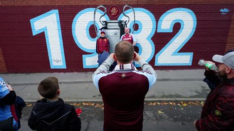 Write informative laconic excerpt under 30 words in mexican spanish for news below. Do not wrap it into quotation marks or html tags. BIRMINGHAM, England -- The echoes of history were inescapable on Wednesday at Villa Park. After a 41-year wait to return to top-level European football, Aston Villa&apos;s 1-0 win over Bayern Munich in the Champions League repeated the scoreline which secured their sole European Cup triumph on May 26, 1982.Just like that memorable night in Rotterdam, where Peter Withe scored the most famous goal in the club&apos;s history over the German giants, Villa were outplayed for periods of the match and had to weather several storms, but they struck against the run of play to secure another famous victory as striker Jhon Durán wrote his name into folklore.Villa&apos;s 1982 triumph is immortalised all around the stadium: a quote of the commentary for Withe&apos;s winning goal hugs the top of the Doug Ellis Stand, while the PA system blared out The Beautiful South&apos;s "Rotterdam" moments before the teams walked out on Wednesday.It was always going to be an emotional evening given that one of the 1982 squad, striker Gary Shaw, passed away on Sept. 16. Memories of Shaw were everywhere: William McGregor&apos;s statue was covered in tributes, Shaw&apos;s name was included at the foot of the Villa team in the match programme, and a seat was reserved for him in the press room.Ahead of kickoff, fans of all ages along Trinity Road were wearing their 1982 commemorative jerseys. One fan even wore the same beer-soaked top he had on in Rotterdam all those years ago -- he said it has been cleaned since, but the stains suggested it has stories to tell.For Villa supporters whose memory stretches back that far -- including Prince William, who was in attendance on Wednesday -- there are two dates etched into their minds: the win over Bayern in 1982, but also their last European Cup night at Villa Park in March 1983, when they lost 2-1 to a Juventus team including legends like Michele Platini, Paolo Rossi, Marco Tardelli and Dino Zoff.Villa have had other dalliances in European football since -- they qualified for the UEFA Cup/Europa League 11 times, their best finish being a quarterfinal against Atlético Madrid in 1998, they won the Intertoto Cup in 2001, and reached the semifinals of the Conference League last season -- but their return to the top table this season is something special.Villa fan Mark Goodwin, who was present over 40 years ago for the games against Bayern and Juventus, was there again for Bayern on Wednesday. This time he brought his father&apos;s ashes with him, to leave near his seat at Villa Park. "[He was] Born and bred in Aston, he went to the 1957 Cup final and loads before. I just had to do it," Goodwin tells ESPN. "This was the biggest night at Villa Park since we played that wonderful team in 1983."The legacy of 1982Aston Villa fans pose for a photo in front of a 1982 champions league themed mural outside Villa Park, Birmingham, ahead of the UEFA Champions League match between Aston Villa and Bayern Munich David Davies/PA Images via Getty ImagesVilla&apos;s captain for the 1982 European Cup final was Dennis Mortimer, who is now part of the club&apos;s honorary anniversary board. His side edged out Ipswich Town to win the old First Division in 1981 -- their first title in 71 years, and a feat he regards as the pinnacle of his career -- to secure a place in Europe for the following season, but manager Ron Saunders&apos; resignation in February (due to a disagreement with chairman Ron Bendall over a new contract) sent shockwaves through the club.Reaching the European Cup final with two-legged wins over Iceland&apos;s Valur, Germany&apos;s BFC Dynamo, Ukraine&apos;s Dynamo Kiev, and Belgium&apos;s Anderlecht, Villa were heavy underdogs as they faced Bayern in Rotterdam under Saunders&apos; old assistant Tony Barton. The Villa team didn&apos;t have a single international player, but Bayern featured three players who would go on to start for Germany in that summer&apos;s World Cup final against Italy.Things started badly for Villa as they lost first-choice goalkeeper Jimmy Rimmer to injury after just nine minutes. But his replacement Nigel Spink -- in only his second appearance -- stood tall, and Withe tapped home in the 67th minute for what would be the most famous goal in club history."Having seen the 1982 match, anything else is a backward step," says Villa fan Nigel Waldron, whose car number plate reads &apos;1982 AV&apos;. Waldron watched Wednesday&apos;s match from Las Vegas having made the holiday booking in January, never expecting his team to be back at the top table. But the hope is that the successes of the 2024 group can ensure the 1982 immortals are remembered forever."What the club&apos;s got to try and do this season is make sure the past is something that is brought to life again for the fans," Mortimer says. "For those young players or these young supporters, this might be the time when they realise Aston Villa in the early 1980s was a very, very big club."You feel not everybody is aware we won this trophy in 1982, and this is what you want to bring home to those younger people: we did have a team that won it once. So the thought will be: Well, can we go on and win it again?"A journey of discoveryVilla fans celebrate their first goal during the UEFA Champions League 2024/25 League Phase MD2 match between Aston Villa FC and FC Bayern Munchen Jacques Feeney/Offside/Offside via Getty ImagesAston Villa&apos;s journey back to European glory hasn&apos;t been straightforward. Five years after they became European champions, Villa were relegated and struggling with debt. They were promoted back the following season and went on to become founder members of the Premier League in 1992, before winning the 1994 and 1996 League Cups, even enjoying more forays into Europe.But they suffered relegation again in 2016, with more financial troubles and new owners before returning to the top flight in 2019. The appointment of former Arsenal, Paris Saint-Germain and Villarreal boss Unai Emery in October 2022 changed things for the better and after finishing fourth last season, Champions League nights have now returned to Villa Park."Who would have thought six years ago, when we were languishing in the lower reaches of the Championship with no hope of even getting out of that division very quickly, that we&apos;d be playing in the top competition in Europe tonight?" Goodwin says.Following every twist and turn has been supporters&apos; club "The Punjabi Villains." Jag Kalaar has been supporting Villa since 1977 and remembers getting his updates via Aston-based radio station BRMB and Radio West Midlands, heading to the newsagents an hour after full-time and picking up The Sports Argus paper (nicknamed &apos;The Pink,&apos; published between 1897 and 2006) before devouring highlights on Match of the Day.Nim Gill became a fan after he received a hand-me-down Villa shirt from his friend&apos;s older brother, but it was a tough task to attend matches. "Due to cultural beliefs and rabid, blatant racism, my parents would not let me go to matches as a youngster," he says. "However, I did sneak away to several."Kalaar adds: "Being Punjabi and Sikh, as well as having the traditional long hair tied in a top knot, it was difficult to attend football games. As we know, racism was rife in the 1970s and &apos;80s and this wasn&apos;t just verbal. I recall my friends and I being chased through the park by skinheads, and we weren&apos;t even at the match, just playing in the local park. Today going to a game with your son or family and friends is a nice experience. The game is open to all, and for me it&apos;s become like a day out, away from the chores of work and general life!"For both, Emery&apos;s first match in charge, when Villa beat Manchester United 3-1 at Villa Park in 2022, is a favourite memory. It was a moment that gave them hope and laid the groundwork for this Champions League run. But the journey to Europe has been fraught with challenges too.Financial pressuresJhon Duran centre-forward of Aston Villa and Colombia celebrates after scoring his sides first goal during the UEFA Champions League 2024/25 League Phase MD2 match between Aston Villa FC and FC Bayern München Jose Breton/Pics Action/NurPhoto via Getty ImagesAs Villa prepared for their return to the Champions League this season, they&apos;ve looked graceful on the surface but have been paddling like mad under the water to keep afloat. Chris Heck, Villa&apos;s president of business operations, has seen the club&apos;s brand grow in recent years as they make strides to right the ship financially, expanding into new territories, signing a new multi-year sponsorship with Adidas, and investing into the training ground. "We&apos;re doing things on and off the pitch that no club in the world is doing," he tells ESPN.Even so, Villa were on the brink of falling foul of the Premier League&apos;s Profit and Sustainability Rules (PSR) in the summer, forcing them to offload star midfielder Douglas Luiz to Juventus for £42 million to avoid a points deduction before the June 30 deadline."We sorted it out at the last second," Villa&apos;s director of football operations Damian Vidagany said in early September. Heck tells ESPN: "We have a path to fight against some elements of PSR that don&apos;t necessarily benefit a challenger club like us. I think we&apos;ve almost passed that challenger realm; we&apos;re now a disruptor."The return to Champions League will be a boost to their finances, but the club hiked ticket prices for their group-stage matches at home -- now four games instead of three under UEFA&apos;s new format. The Aston Villa Supporters&apos; Trust called the pricing "out of touch" and "extremely disappointing," with adult tickets ranging from £75-£97 -- the equivalent of an £85 ticket costs £55 for Premier League home matches (season-ticket holders&apos; prices for the Champions League range between £70-£82.) With this year being Villa&apos;s 150th anniversary, there is added pressure to make this season&apos;s Champions League campaign a celebration of everything claret-and-blue."We&apos;ve been working for six months on this, and we built a committee," Heck says. "This is with former players, former coaches, current fans and supporters. It&apos;s a robust group. We&apos;re the first big club to turn out 150 years, and so this is a global play. We&apos;re going to set the bar very high, and we think that we&apos;re going to leave a lot of memories. It&apos;s not going to be one day; it&apos;s not going to be one game. It&apos;s going to be an entire year."Will Europe help or hinder their progress?playKompany: Bayern&apos;s loss to Aston Villa won&apos;t decide Champions LeagueVincent Kompany reacts to Bayern Munich&apos;s 1-0 defeat to Aston Villa in the Champions League.Villa have made a good start to the Premier League -- fifth in the table, with four wins, a draw and a defeat -- but the wear and tear of a European campaign will disrupt momentum and Mortimer has concerns about the impact playing in four competitions will have on Emery&apos;s squad."He&apos;s got 38 [league] games where he&apos;s got to put his best team out. He&apos;s got eight games now in the Champions League," he says. "So that&apos;s a lot of games where pressure and everything else that goes with it is going to be coming down on the players. But at the same time, it&apos;s exciting for the team, it&apos;s exciting for the players, it&apos;s exciting for the fans. So it can only be a good thing, to be honest."Thus far, it has been a very good thing. On Sept. 17, Villa thrashed Switzerland&apos;s Young Boys 3-0 away from home in their first game and on Wednesday, they beat one of Europe&apos;s biggest clubs. Bayern had the better chances and the bulk of possession, but Villa had goalkeeper Emi Martinez and the Argentina international produced two brilliant late saves to preserve the lead established by Durán&apos;s 79th-minute goal."It was amazing. I am so, so happy for the fans that they responded like they did," Emery said afterward. "We are trying to transmit that energy and connect with them. If we connect, we can get that energy on the field. Tonight was very important."On the Holte End there&apos;s a banner reading: "Do you want to bet against us?" Those were Saunders&apos; immortal words as his team entered the final stages of their two-horse race with Ipswich for the First Division title in 1981. Few would now bet against Villa making a dent in this competition after witnessing what they did on Wednesday, and there will be more memorable nights to come, with Villa hosting Juventus on Nov. 27. "That&apos;s the one I am looking forward to as they knocked us out the following year [in 1983]," Waldron says.The efforts of the 1982 legends will never be forgotten; their success helped build the foundations the club now find themselves on. "From Aston Villa&apos;s point of view, 1982 is the biggest part of the history of the football club at this moment," says Mortimer.A couple of hours after full-time against Bayern, there were still Villa fans in and around the stadium, soaking up the atmosphere. They clutched flags and keepsakes; they replayed the Durán goal on their phones as they waited for taxis after another special European night."This game was for all those fans who stuck by us in the tough times and witnessed heavy home defeats and a meagre three wins all season in our relegation year of 2016," Goodwin says. "To have played against Bayern in our first home match in the Champions League is an absolute dream come true. Under Emery, anything is possible." ,Aston Villa regresa a la Champions League con una histórica victoria 1-0 sobre el Bayern Munich, recordando su gloria pasada en 1982. La afición revivió la emoción.