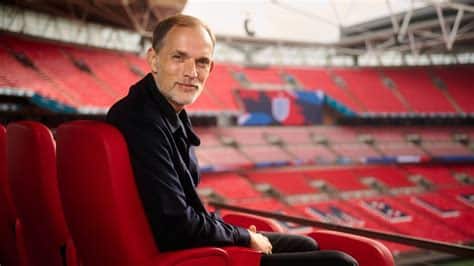 Write informative laconic excerpt under 30 words in mexican spanish for news below. Do not wrap it into quotation marks or html tags. play&apos;Sorry I have a German passport!&apos; - Tuchel on England fan backlash (1:42)Thomas Tuchel says he is "proud" to be England&apos;s manager and speaks about whether he will sing the national anthem. (1:42)New England head coach Thomas Tuchel has said he will not shy away from publicly stating his aim is to win the 2026 World Cup and believes only "nuances" and "details" have stopped the side ending their long wait for silverware.Gareth Southgate came closer than any manager since Sir Alf Ramsey to delivering England&apos;s first men&apos;s trophy since 1966, guiding the team to back-to-back Euros finals.Southgate stepped down after losing the Euro 2024 showpiece to Spain in July and the Football Association (FA) responded by appointing under-21 manager Lee Carsley on an interim basis before pivoting to a proven winner in Tuchel.Sources have told ESPN that Manchester City boss Pep Guardiola was among the 10 candidates FA chief executive Mark Bullingham revealed on Wednesday that they had spoken to during the process.However, they ultimately chose Tuchel, who has won 11 major honours at club level including the 2021 Champions League with Chelsea.The 51-year-old will start his 18-month contract on Jan. 1 -- meaning he will get just one tournament cycle as things stand -- and when asked if it was win or bust for him with England, Tuchel said: "I don&apos;t know, it depends. I know what you&apos;re saying. No, it&apos;s not a gamble, but we speak it out now very clearly why we are here and what we want to achieve.Thomas Tuchel was appointed as England manager on Wednesday. Michael Regan - The FA/The FA via Getty Images"We are not shy of it. We are absolutely open about it. It does not help the more often we speak about it, but it should be out there and then we can set the standards and set the values and principles because then we have to live up to them for 18 months."Let&apos;s judge it when we have done it. If we decide it was a failure, then we will not continue. If we decide it was not a failure, then we will continue. Let&apos;s see. No one can predict the future."It feels absolutely right for me to do so, it feels clear and it feels easy for me to explain. When it&apos;s easy to explain, it&apos;s normally good."We are playing with players for the best league and the biggest competition in the world. We have a group of young hungry players. We are desperate to win a title, so we have all the ingredients, so I think we should try to implement this into our style of play."I think we should play an attacking style of football and we should try to emphasise a physical side of the game because this is what English football is all about and this is what excites our supporters, and this is what suits the players."Southgate led England to the 2018 World Cup semifinals where they were beaten in extra-time by Croatia. They lost the Euro 2020 final on penalties before exiting the World Cup two years later with a narrow 2-1 defeat to France in which Harry Kane missed a late penalty that would have tied the score.Spain edged another tight game 2-1 in Berlin and when asked to explain what England were missing, Tuchel said: "I think it&apos;s just nuances, it&apos;s just details. If you lose on penalties in a final, who would I be to say I know what you did wrong when you were there."You were there. We or they have been in two finals I think. Semifinals and quarterfinals. Lost each of them very, very close, each of them could have gone either way. The genuine belief is that we are there, that we are ready."Bullingham also defended the appointment of a foreign-born manager -- the third in England&apos;s history -- despite the FA making the development of homegrown players and managers at St. George&apos;s Park central to their mission.Citing the arrival of English coach Anthony Barry as Tuchel&apos;s assistant, Bullingham said: "If you look at St. George&apos;s Park overall, I think it has been a really good success. Our pathway is really strong, both from a coaches and players point of view. There are a lot of fantastic young coaches around and obviously Anthony is one of those."I think any federation in the world that is looking to hire a senior manager, clearly you would love to have five to 10 domestic candidates who are coaching clubs in your domestic league, challenging and winning honours in your domestic league and European football. We are not quite in that place at the moment."Tuchel confirmed he will be living in England and explained why he will not take charge immediately with Carsley remaining in post for next month&apos;s UEFA Nations League games against Greece and Republic of Ireland."It was important for me to narrow it down into a project and not lose the focus, to start in another competition, the Nations League, then go into qualification and the tournament," he said."I wanted to have a clean start and a bit of time to recharge fully and start in January and start the first camp in March." ,Nuevo seleccionador de Inglaterra, Thomas Tuchel, apunta al objetivo de ganar la Copa del Mundo 2026. El exentrenador del Manchester City, Pep Guardiola, entre los candidatos.