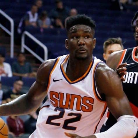 Write informative laconic excerpt under 30 words in mexican spanish for news below. Do not wrap it into quotation marks or html tags. Deandre Ayton, jugador de los Suns de Phoenix, promedió 18 puntos y 10 rebotes en la temporada 2022-23, su quinta temporada consecutiva promediando un doble-doble. Aunque sus promedios de rebotes y rebotes ofensivos disminuyeron, Ayton estableció nuevos máximos en tiros libres. Sorprendentemente, Ayton fue intercambiado por Jusuf Nurkic en una importante negociación que llevó a Damian Lillard a los Bucks de Milwaukee. Ahora, Ayton será el centro titular de los Trail Blazers de Portland. Sin Kevin Durant y Devin Booker en el equipo, se espera que Ayton tenga mayor protagonismo en la ofensiva del equipo y pueda tener buenas actuaciones individuales. Aunque Ayton ha mostrado progreso desde que fue seleccionado como la primera selección global en 2018, algunos dudan de su potencial y lo consideran un jugador limitado en fantasy debido a su estilo de juego tradicional y sus fortalezas en rebotes y porcentaje de tiros de campo. Sin embargo, se espera que el dúo formado por Ayton y Chris Paul en los Suns de Phoenix, junto con su confianza adquirida en los playoffs, lo lleve a alcanzar nuevos niveles en ambos extremos de la cancha y a convertirse en uno de los mejores jugadores interiores de la NBA.,Deandre Ayton, de los Suns a los Blazers: Cambio sorprendente que dará mayor protagonismo al centro en Portland tras establecer máximos en tiros libres. La confianza adquirida en playoffs impulsará su juego.