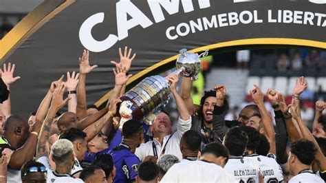 Write informative laconic excerpt under 30 words in mexican spanish for news below. Do not wrap it into quotation marks or html tags. U.S. businessman John Textor lifts the Copa Libertadores trophy after Botafogo&apos;s 3-1 win. Luis ROBAYO / AFPBotafogo can now party like it&apos;s 1959, when the likes of Garrincha, Zagallo, Didi and Nilton Santos, some of the all-time greats of the Brazilian game were at their peak in the club&apos;s colours.Recent times have provided a sad contrast with a glorious past. Botafogo have spent many recent decades as the fourth team of Rio de Janeiro, playing in front of small crowds and relegated three times to the second division -- where they were when U.S. businessman John Textor took over the club in 2021. And now, three years later, they have become champions of South America for the first time, winning the Copa Libertadores with a gripping 3-1 triumph over fellow Brazilians Atletico Mineiro in Buenos Aires on Saturday.The club is known for its attachment to superstition. Often trotted out is a phrase -- with a considerable dose of self-pity -- which holds that "there are things that only happen to Botafogo."Supporters had good cause to remember the phrase at the start of the match. Saturday&apos;s Libertadores final shaped as the most important game in the history of the club. And less than 30 seconds after the kick-off, midfielder Gregore flew into an ugly high tackle, caught his opponent in the head, and was sent off.A game where Botafogo took the field as clear favourites instantly changed its complexion. The expectation was that the Botafogo front four would impose themselves on the game, that a forward line assembled by Textor&apos;s club with a combination of deep pockets and excellent scouting would click into irresistible form. And now it was a case of running, covering, sacrificing, weathering the storm and trying to get through the next few minutes.As a spectacle, the game suffered from the immediate red card. But in another sense, it became even more gripping, ever more heroic. Because Botafogo were now confronted by their demons.The first title of any cycle is always the hardest. And it seemed that the first title was going to come in 2023. To general surprise, including their own, Botafogo built up a massive lead in the Brazilian Serie A. It seemed as if they could not possibly be caught; until they produced one of the all-time, most spectacular collapses. Not only did they fail to win the league, they finished in fifth position -- meaning that they had to go through the qualifying rounds of this year&apos;s Libertadores.With Textor&apos;s investment -- and the excellent scouting policy -- kicking in, this year&apos;s team is a great improvement on the class of &apos;23. And yet, the concept of collective trauma exists. In some of the previous rounds of the Libertadores Botafogo wobbled and flirted with throwing away a winning position. There was a sequence of poor results in the league. Maybe it was all too much? Perhaps the team was not mentally prepared for success?Any such doubts now have to be scratched. On Tuesday they took a giant stride towards the domestic league title with a 3-1 win away to direct rivals Palmeiras. It was a morale boosting result, but it came at a cost. One centre-back, Angola international Bastos, picked up an injury that forced him out of the Libertadores final. There would be other tired limbs in the continental decider just four days later. And now they found themselves having to play the entire game against Atletico with 10 men. Indeed, there are things that only happen to Botafogo.And those things now include winning from such a disadvantaged position. The nature of this triumph, sweated out in the Spring Argentine sunshine, makes it even more valuable. Botafogo have scaled Everest the hard way.Marlon Freitas, left, and Danilo, right, celebrate Botafogo&apos;s Copa Libertadores triumph as the final whistle sounds. Buda Mendes/Getty ImagesIt helped that their opponents Atletico were so clearly short of confidence. They looked like a team that had gone 10 games without a win. There was no conviction in their attacking play. Veteran striker Hulk was a one-man band. Botafogo gradually played their way into the game, sporadically moving upfield. Over the course of the last month, goalkeeper Éverson had been Atletico&apos;s hero, coming to the rescue time and time again. He chose the wrong time to have a bad few minutes. He could have done better with the Luiz Henrique shot that gave Botafogo the lead. And then, in a situation of no danger, he came clattering out of his goal to bring down the winger and give away a penalty, tucked away by Alex Telles.Atletico could get no worse. Coach Gabriel Milito may well have wanted to make 10 changes at half-time. He contented himself with three, and it was enough to change the game. Hulk went out to the right wing, where he found more space, and Eduardo Vargas came on to work a dual centre-forward system with Deyverson. Instantly Vargas headed home from a Hulk corner. Game on. Pressure, attacking threat, desperate clearances, time moving all too quickly for Atletico fans, agonisingly slowly for Botafogo&apos;s.Vargas had two more chances. They went over the bar. Botafogo were running down the clock. The drama deserved something more than a timid ending. It got one. Botafogo brought on winger Junior Santos, who was in hot form at the start of the season but had just made it back from a lengthy injury lay-off. The 30-year-old is like a horse that can run cross country and do the dressage. And with a combination of power and dainty footwork he sealed the game with a goal right at the end. As befits this Botafogo team, the title was sewn up with a moment of class to go with all the grit they had needed to find.It is not entirely clear what the future holds for this current side. Things are still very early in this new era of Brazilian clubs being run on business lines. Will the side be broken up, with players sold off to Europe? Some of this will surely happen. Textor, after all, owns clubs in France and Belgium, and seems keen to get rid of his 49% stake in Crystal Palace in order to have a controlling position in another Premier League club.Can Botafogo justify the amount of money that Textor has invested in this team? The answers are not clear. But at the moment this is hardly a concern for many of the supporters. They do not have to go far back to recall dismal days in the second division. Now they are champions of South America. Let them party like it&apos;s 1959. ,Botafogo celebra su primera Copa Libertadores con una victoria 3-1 sobre Atletico Mineiro en la final histórica en Buenos Aires.